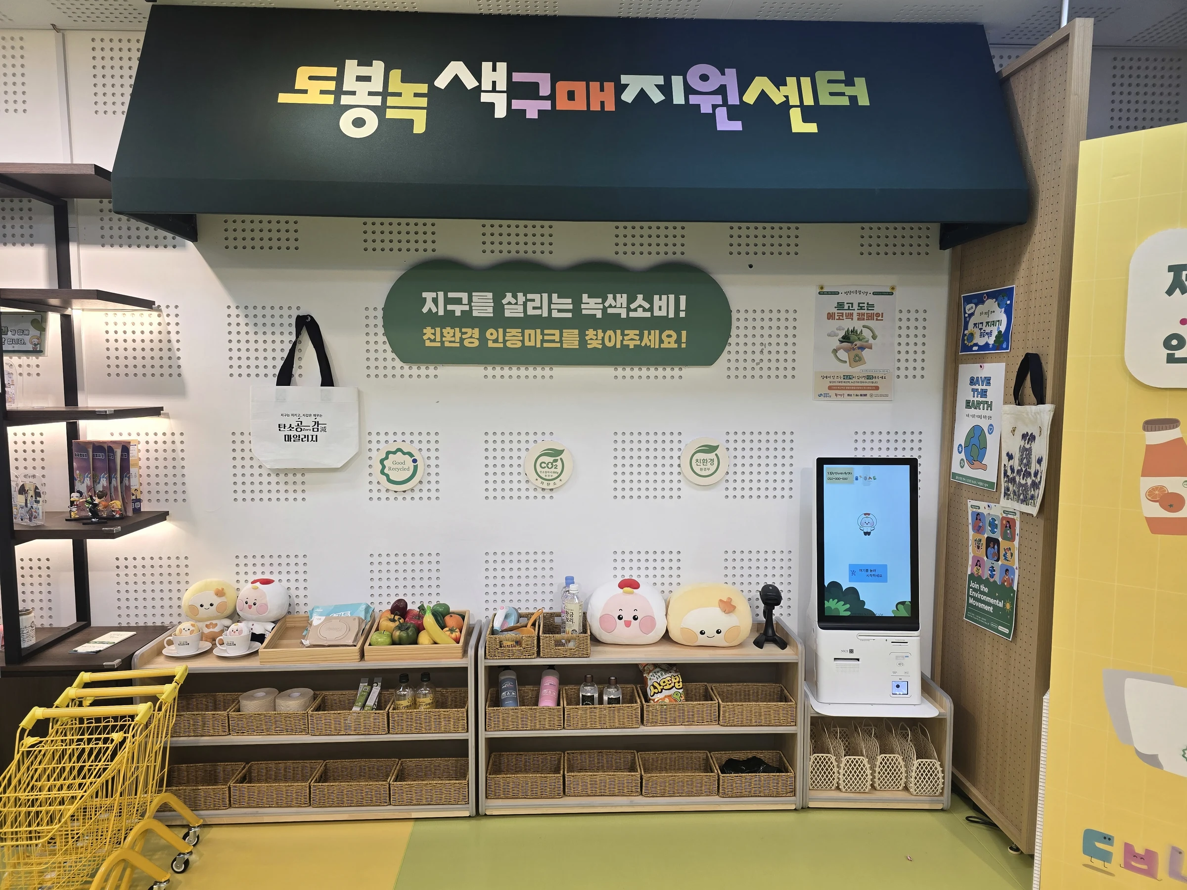 어닝 아래 녹색제품 진열대와 제로씨 녹색체험마트 키오스크